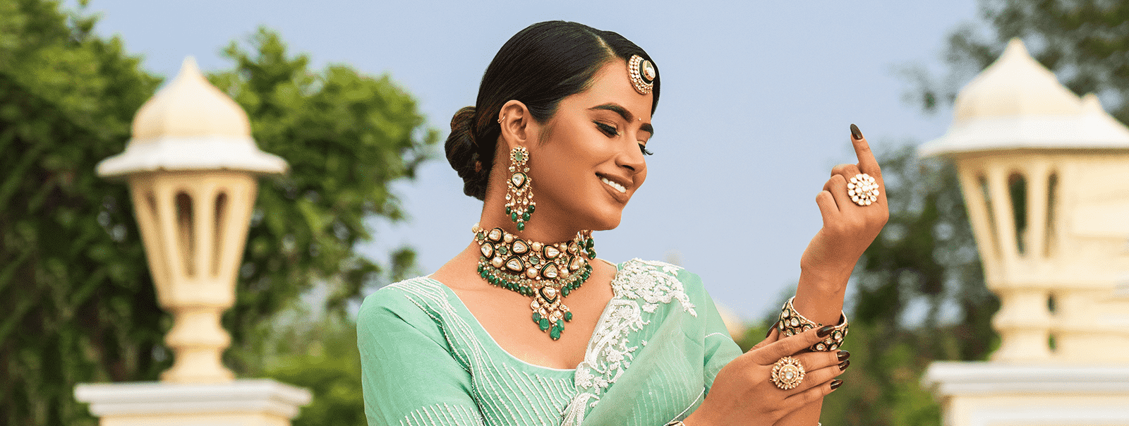 a woman in a green dress holding a polki kada